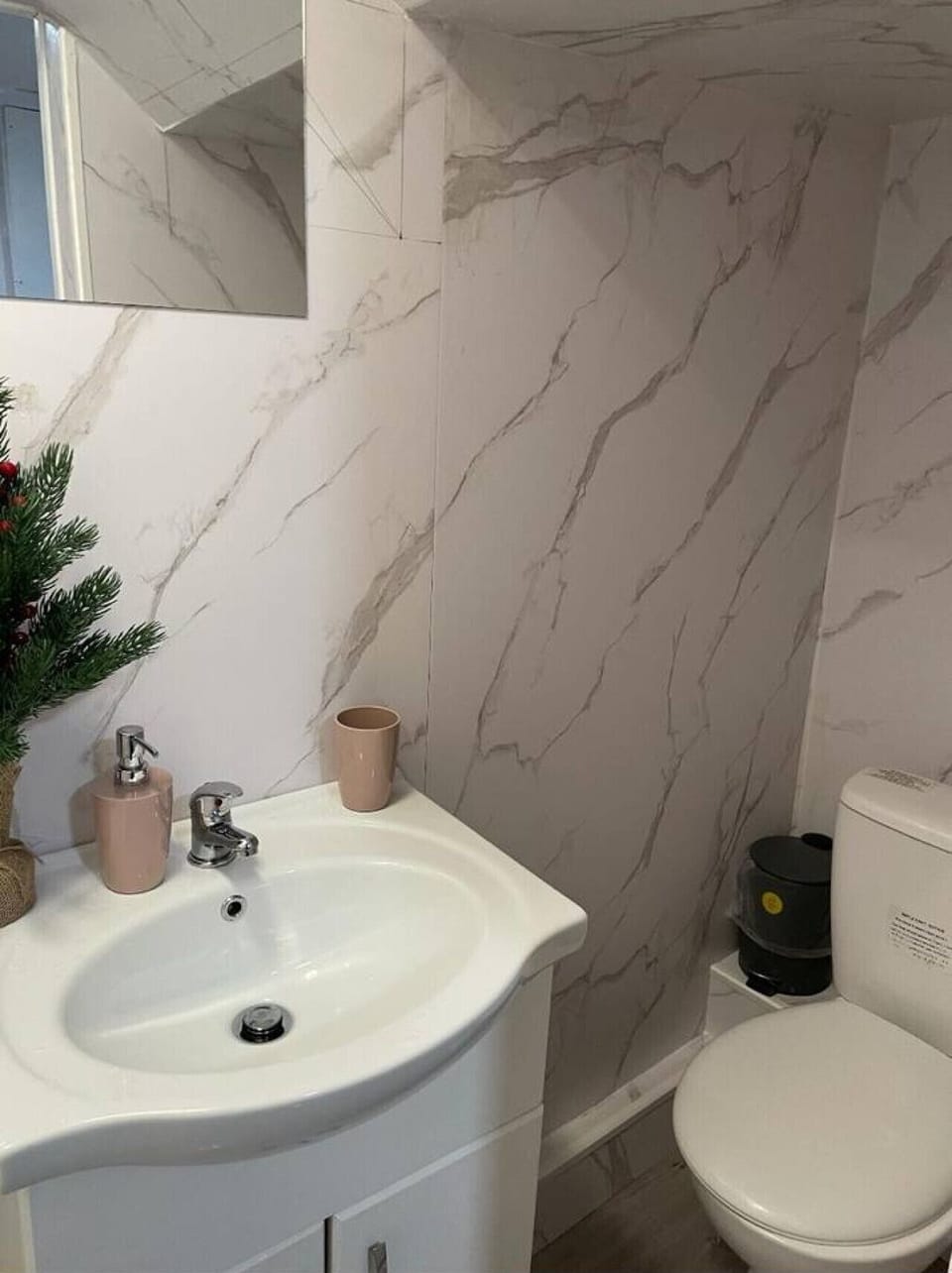 Clean bathroom with sink, toilet, and marble-style walls