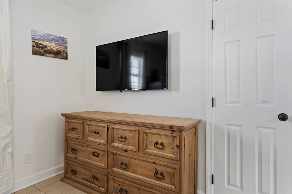 A stylish bedroom corner featuring a wooden dresser and modern amenities provides a serene retreat after a day at the beach.