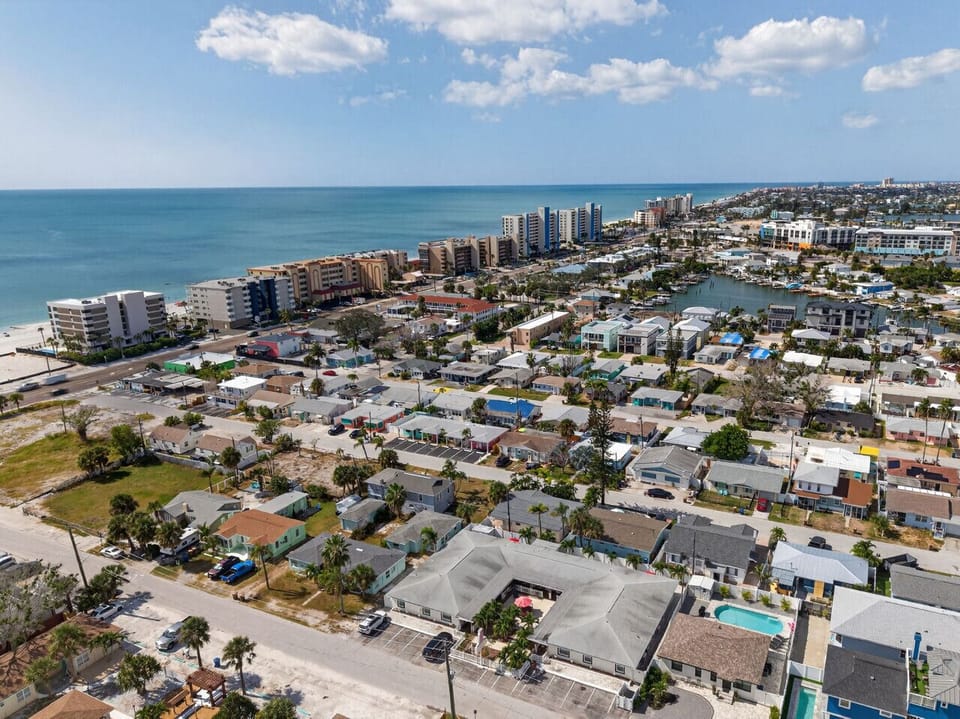 Sweeping aerial showcasing coastal homes w/ the shoreline in the distance.