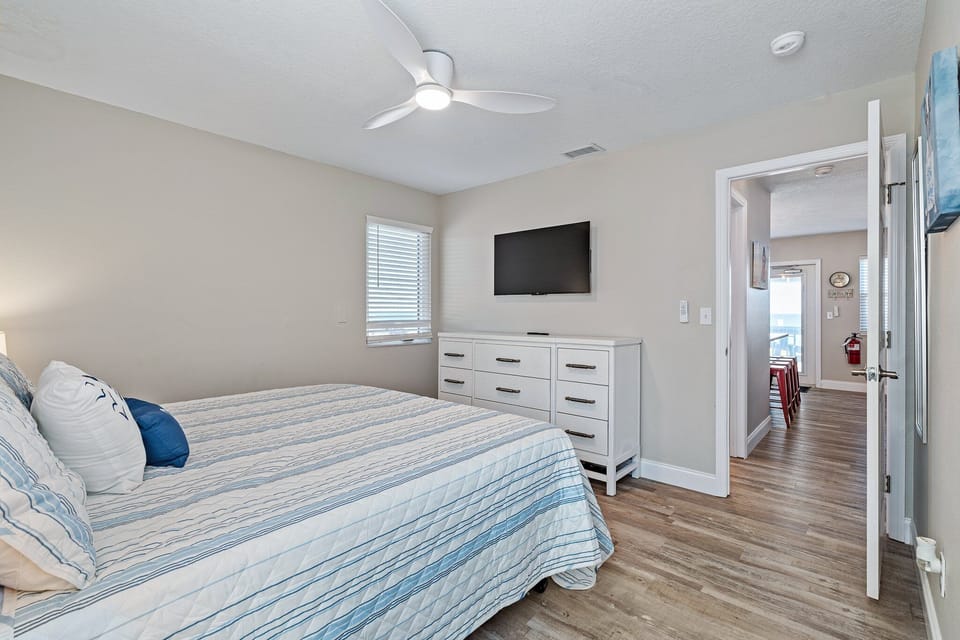 A flat-screen TV and ample storage make it easy to settle in, while a large window fills the room with natural light, creating a bright and breezy atmosphere perfect for unwinding after a day in the sun.