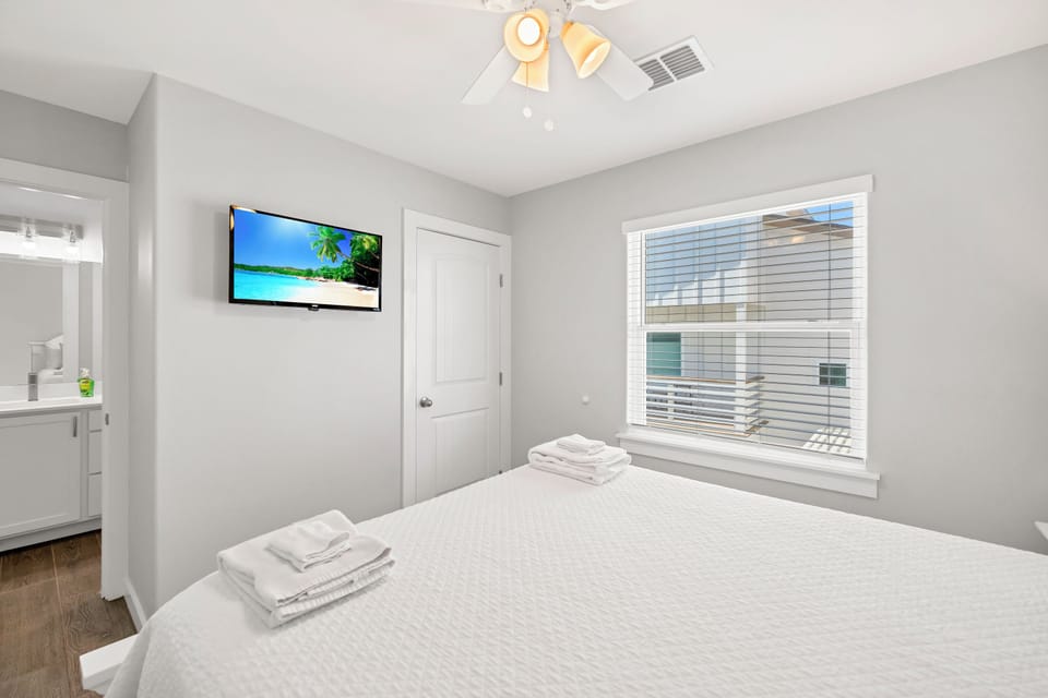 Unwind in your serene bedroom with plush linens, wall-mounted TV, and fresh towels awaiting your arrival.