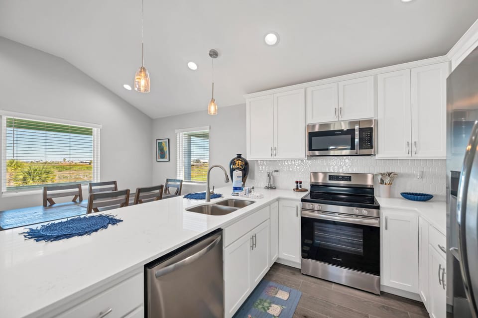 Cook with ease in your fully equipped modern kitchen, featuring white cabinetry, stainless appliances, and a breakfast bar for casual dining.