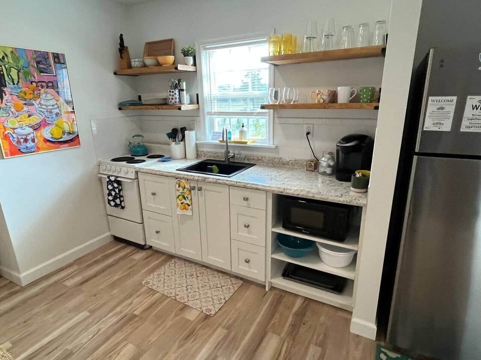 Beautiful open kitchen space with stove, oven, full size refrigerator/freezer, microwave, air fryer/toaster oven, pots/pans, and plenty of dishes to enjoy your time at “home”.