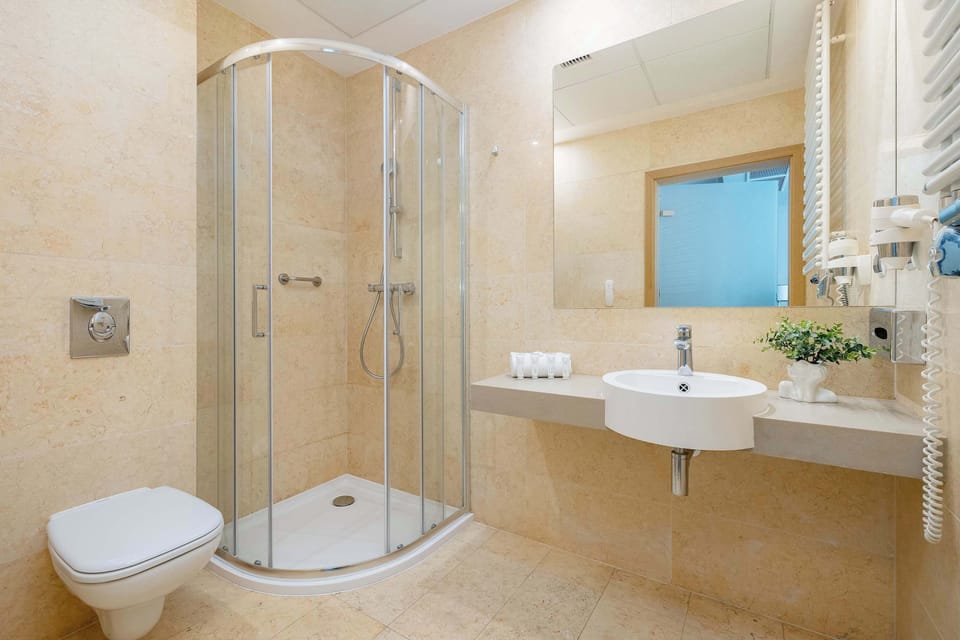 The bathroom features a sleek, contemporary style with bright tiles, a large mirror, and soft lighting for a fresh and comfortable feel.