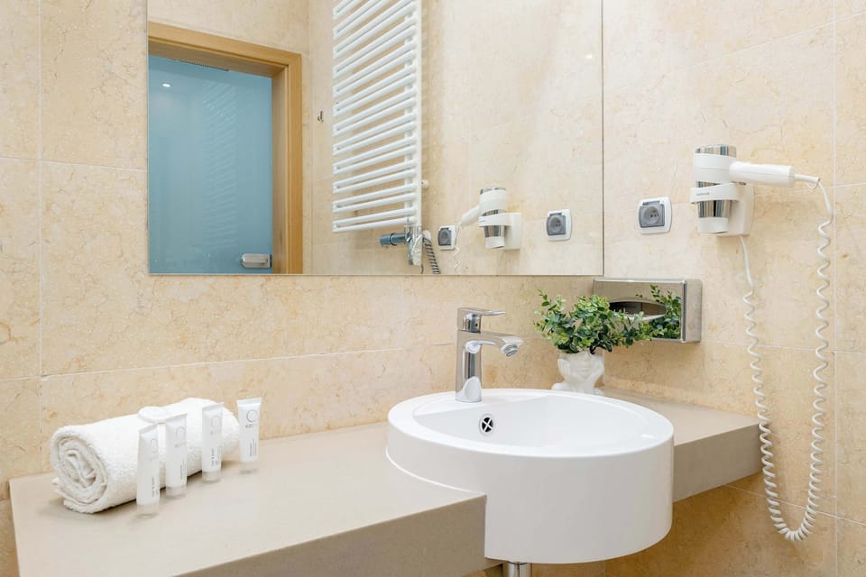Another angle of the bathroom showcasing bright tiles, a wall mirror, and modern sanitary ware.