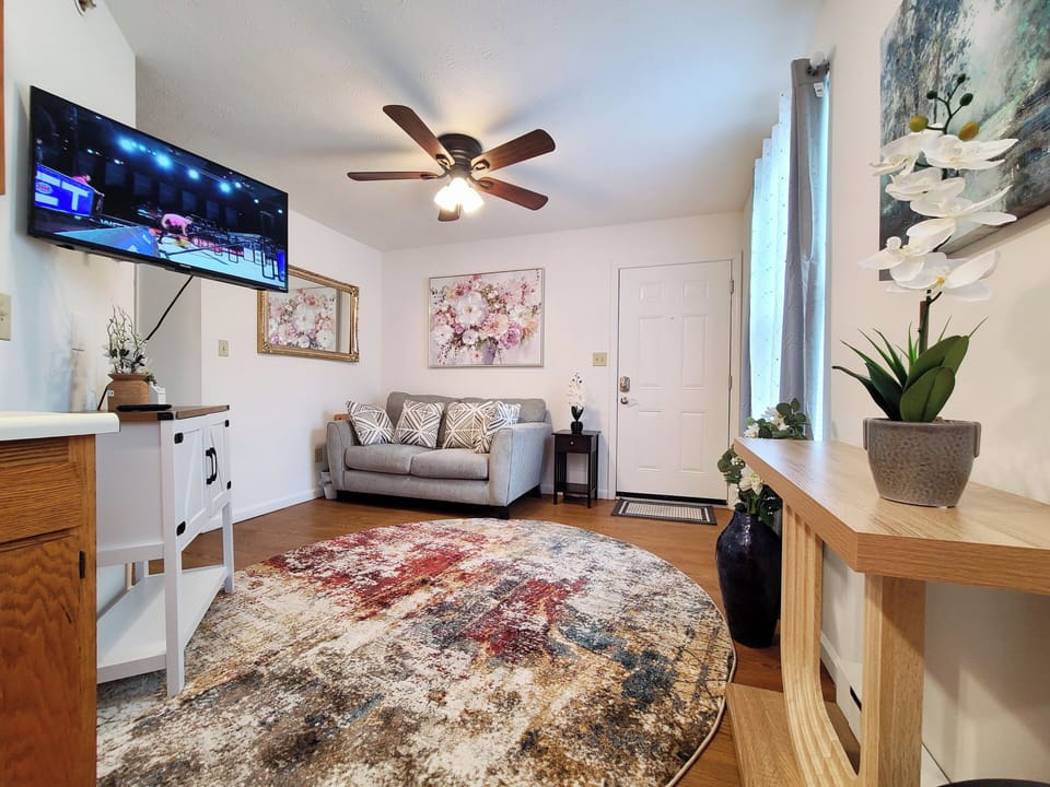 Bright, cozy living room with TV, loveseat, and chic décor—perfect for relaxing.