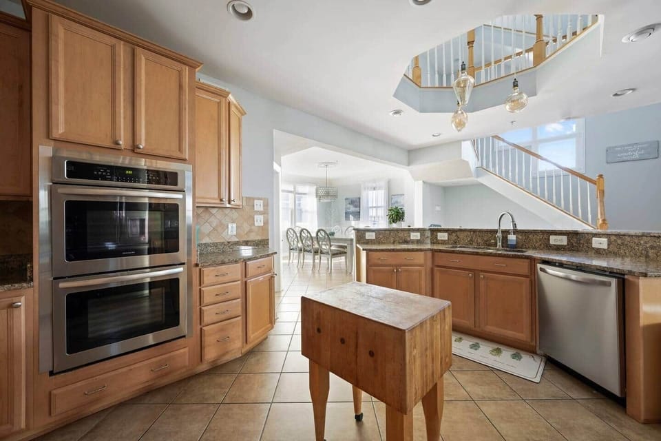 Inside of the kitchen showing ample cabinet space, butcher block island, dishwasher and double oven.