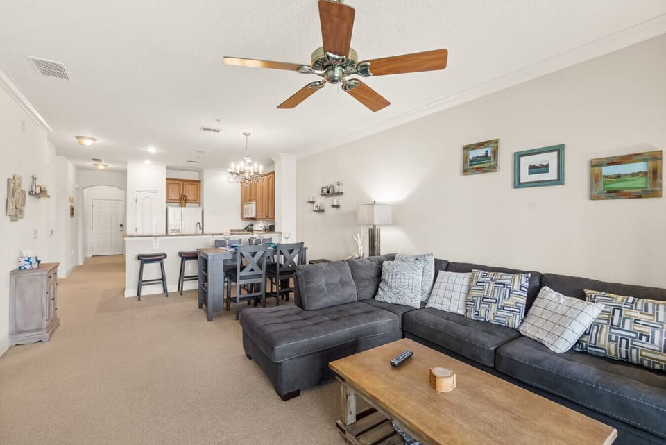 Spacious open-plan living room with comfortable sectional seating and plenty of natural light — ideal for relaxing or movie nights