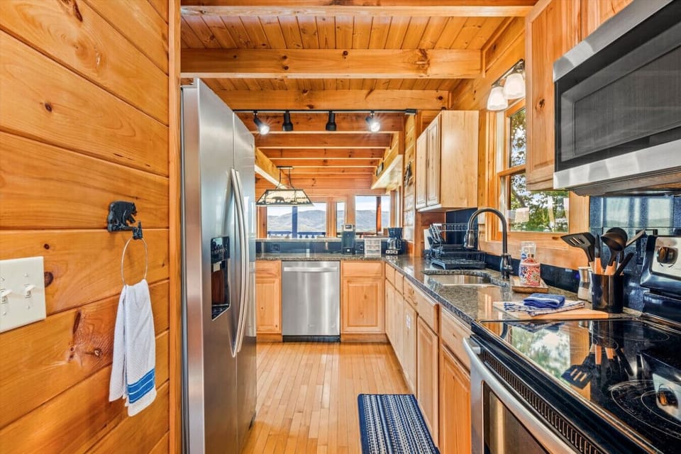 Whip up your favorite meals in this fully stocked kitchen, where stainless steel appliances meet warm wood finishes—and those breathtaking Smoky Mountain views steal the show from every angle.
