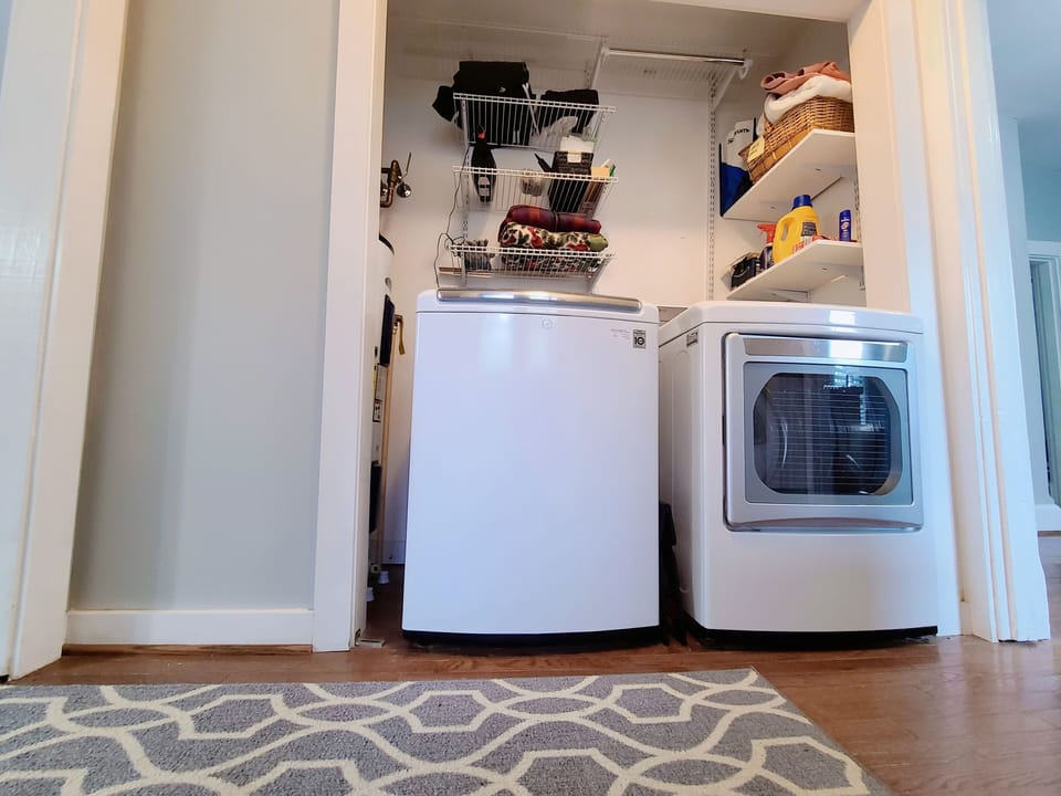 Convenient laundry area with washer, dryer and shelving for easy organization.