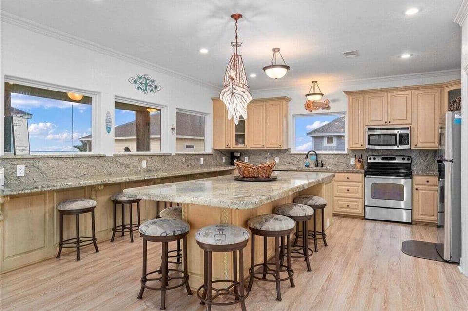 Open kitchen and dining space with island seating, pendant lighting, and ocean-facing windows.