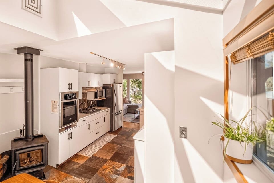Bright, open-concept kitchen with skylights and a cozy wood stove—where modern comfort meets West Coast charm.