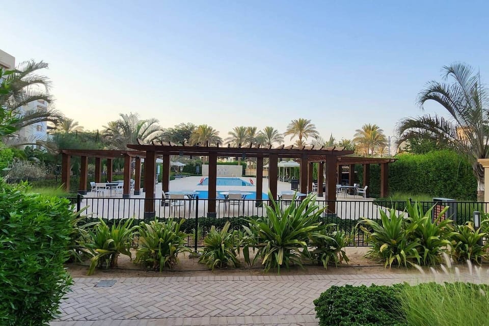 "Step into your private oasis—this beautifully landscaped entrance leads to a serene pool area framed by palm trees and garden paths."