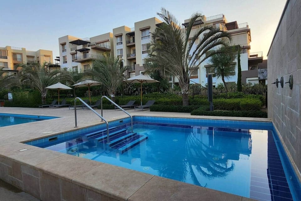 "Dive into relaxation with this serene pool and jacuzzi combo—surrounded by palm trees and lounge chairs for the ultimate holiday vibe."
