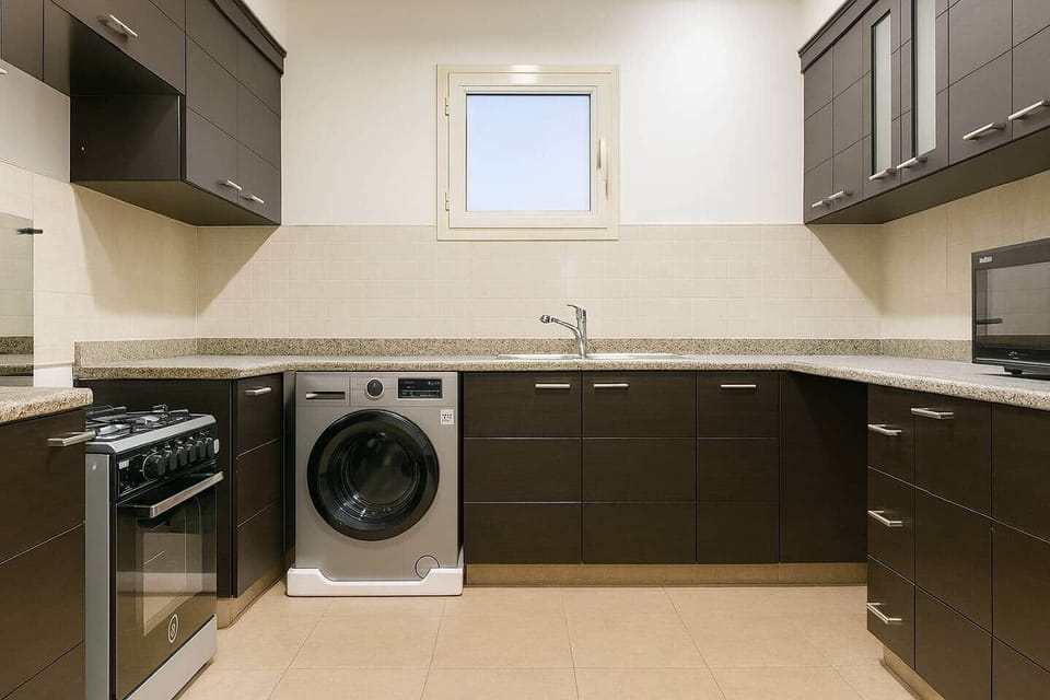 Modern kitchen with granite countertops, dark wood cabinets, full appliances, and bright lighting—ideal for long stays.

