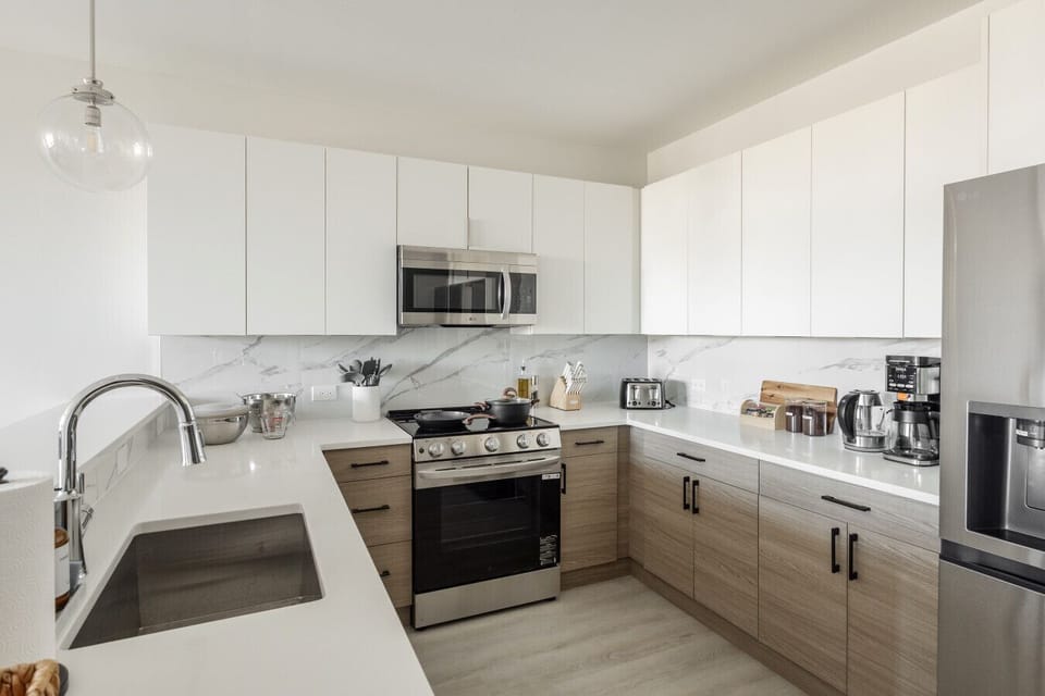Kitchen with oven, microwave, fridge, dish washer, coffee maker, tea kettle, tea, coffee, mixer, mixing bowls, kitchen utensils, toaster