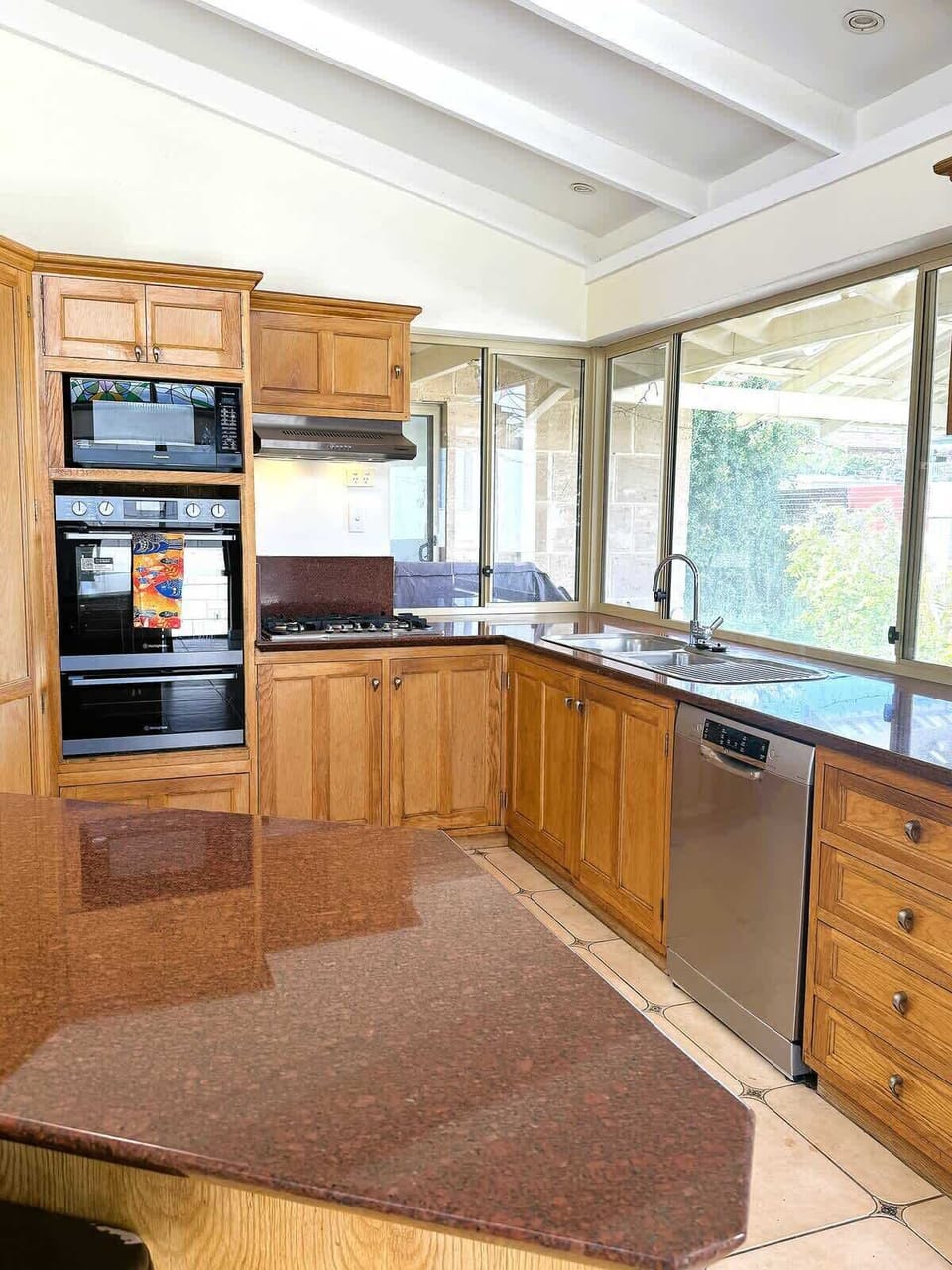 This bright, open-concept kitchen features warm oak cabinetry, sleek granite countertops, and premium built-in appliances. Whether you're brewing morning coffee or prepping a gourmet dinner, the expansive windows provide the perfect sun-drenched back