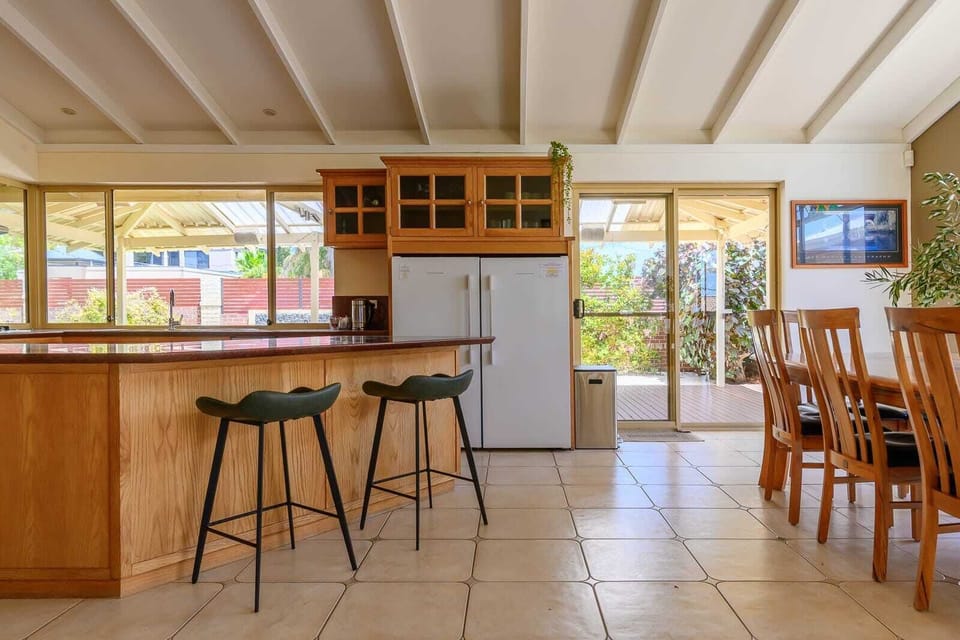 Enjoy the best of both worlds with this sun-soaked living area. Large sliding doors lead directly from the kitchen to the covered patio, while the massive windows and white-beamed ceilings keep the interior feeling light, airy, and incredibly spaciou