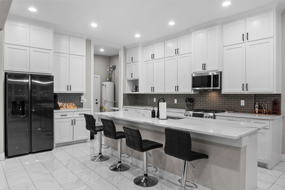 Modern kitchen with white cabinets, big island, bar seating, and natural light.