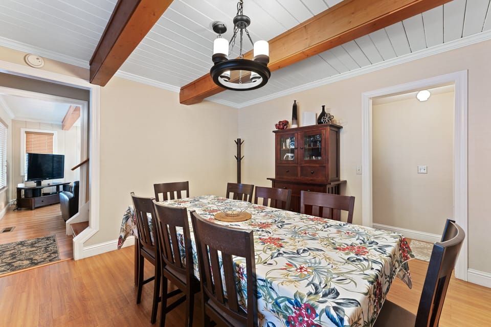 Dining table for seven with chandelier, china cabinet, coat rack, and living room seating in view.