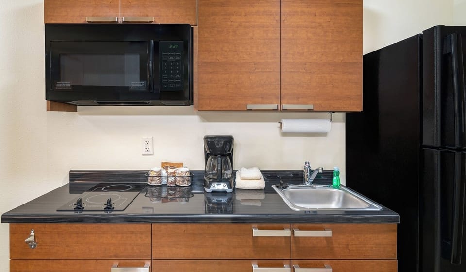 Cook and sip coffee with microwave, cooktop, and fridge.