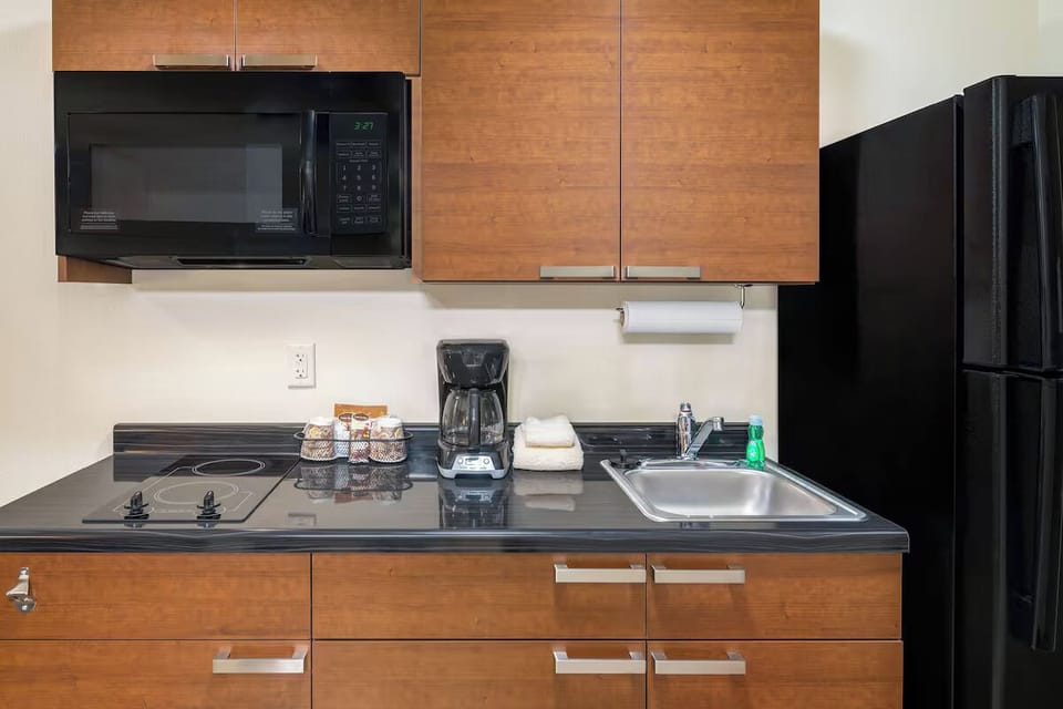 Prep simple snacks with smooth cooktop, sink, and microwave nearby.