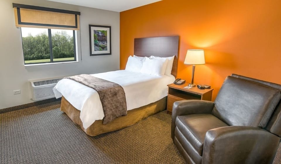 Recharge on a crisp king bed beside a cozy armchair.