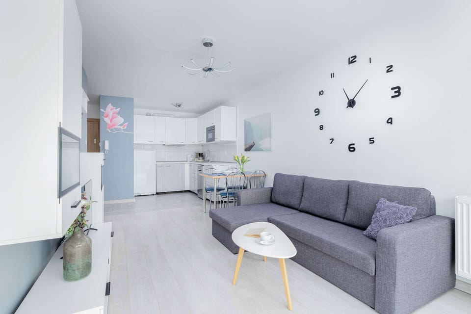 Cozy living room with a gray sofa, wall-mounted TV, and modern minimalist décor.