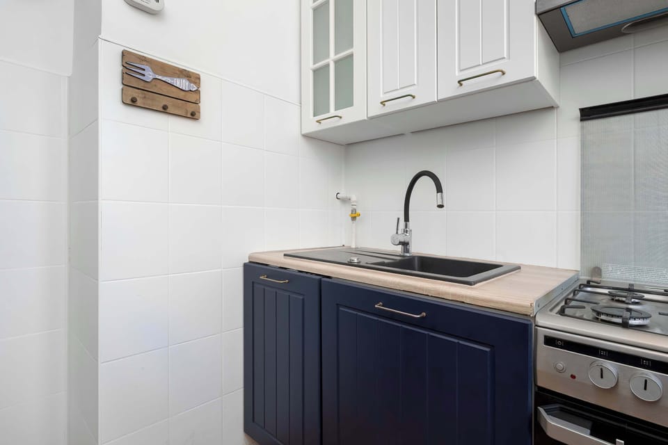 Another angle of the same kitchen showing white tiles, a sink, and upper cabinets. The mix of blue and white adds a modern touch.