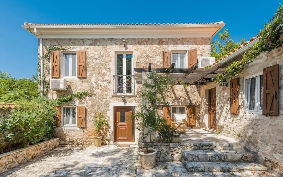 Grand Stone Entrance with Garden Path & Rustic Details
A classic Greek stone facade with arched doorway and courtyard views, combining heritage architecture with tranquil natural surroundings.