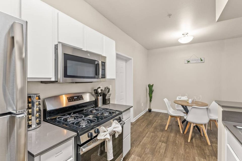 Modern kitchen with stainless steel appliances and cookware provided.