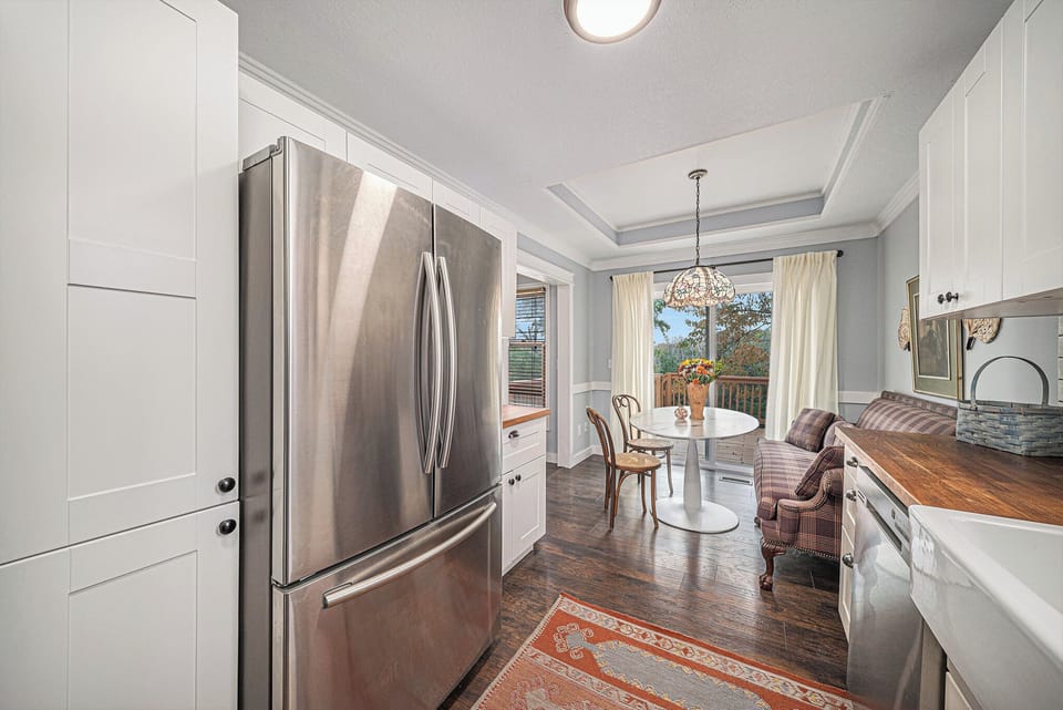 Bright eat in kitchen with cozy seating and peaceful deck views.