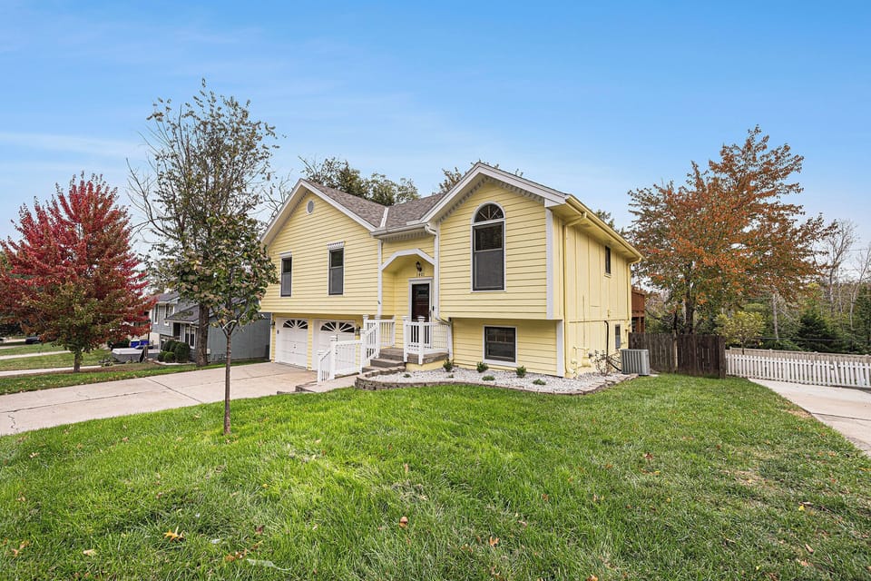 A welcoming front exterior with a spacious yard and driveway, giving a clean and