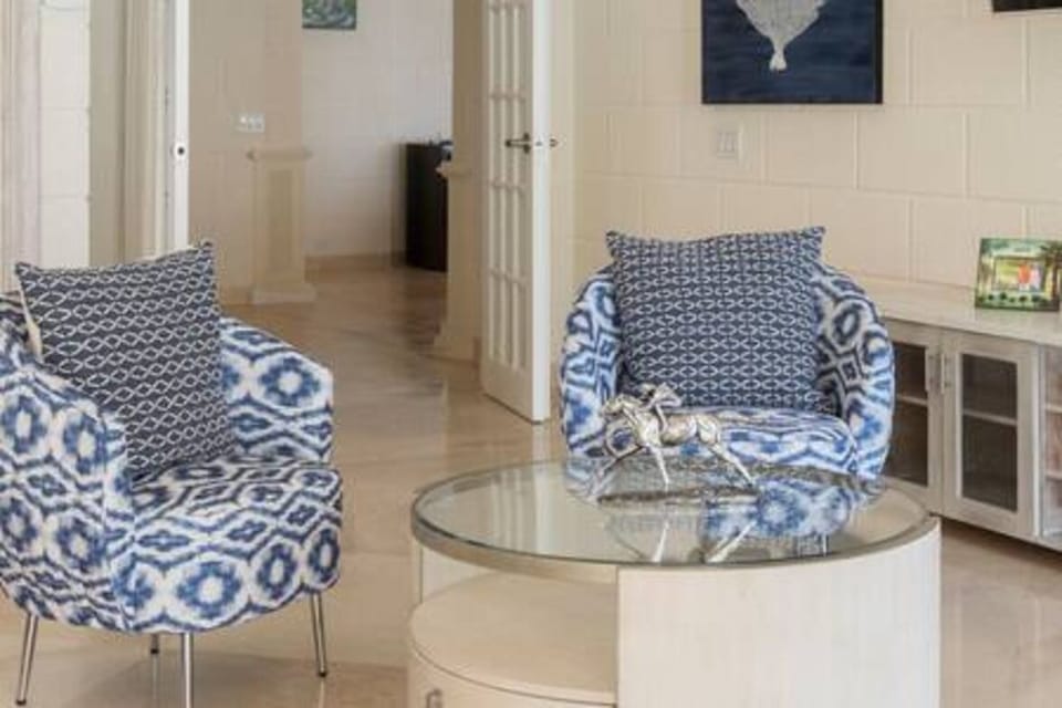 The master suite offers generous space to unwind, plus a shared balcony with Bedroom 2. Features include air conditioning, ceiling fan, TV, Sonos, safe, walk-in wardrobe, and an en suite with freestanding bath and separate shower.