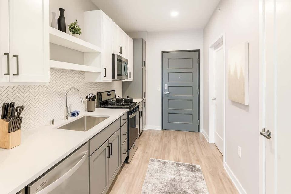 Sleek, fully stocked kitchen with stainless-steel appliances, soft-close cabinets, and a clean open entry leading into the living space.