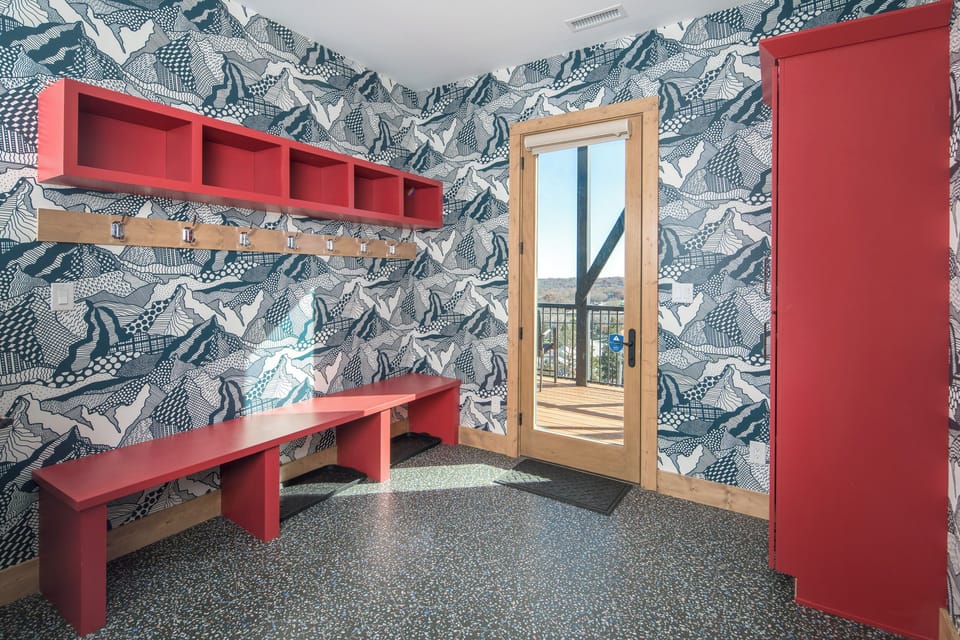 Bold mountain-themed mudroom with red accents and hooks.
