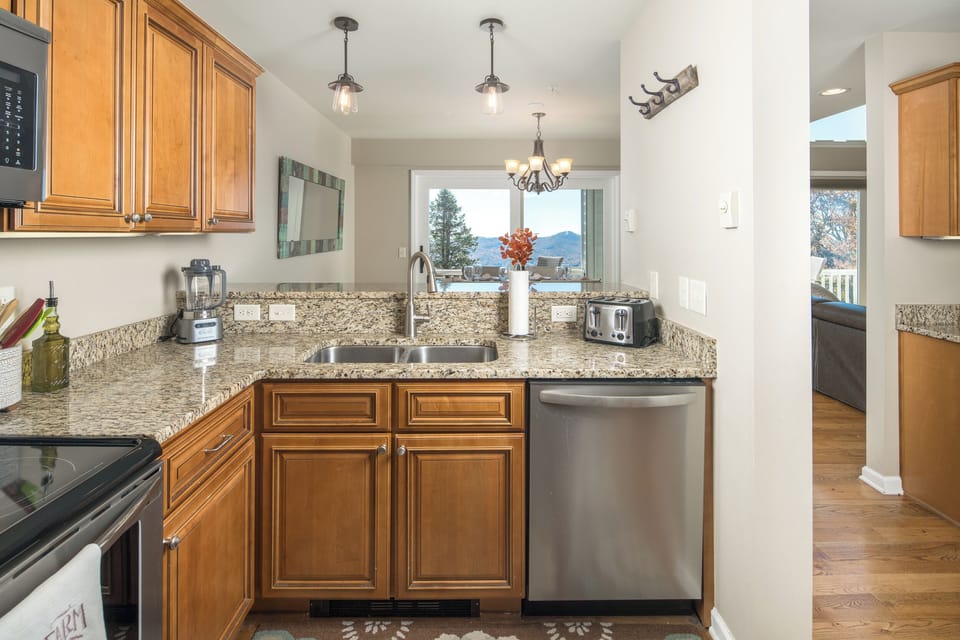 Granite countertops and stainless appliances with a mountain view.