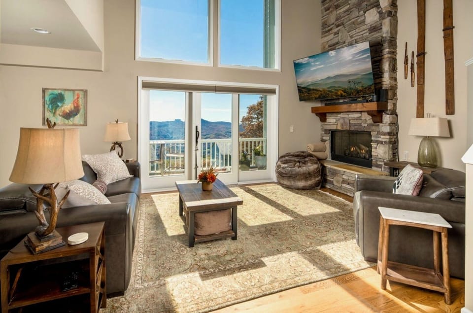 Bright living room with mountain views and a cozy stone fireplace.