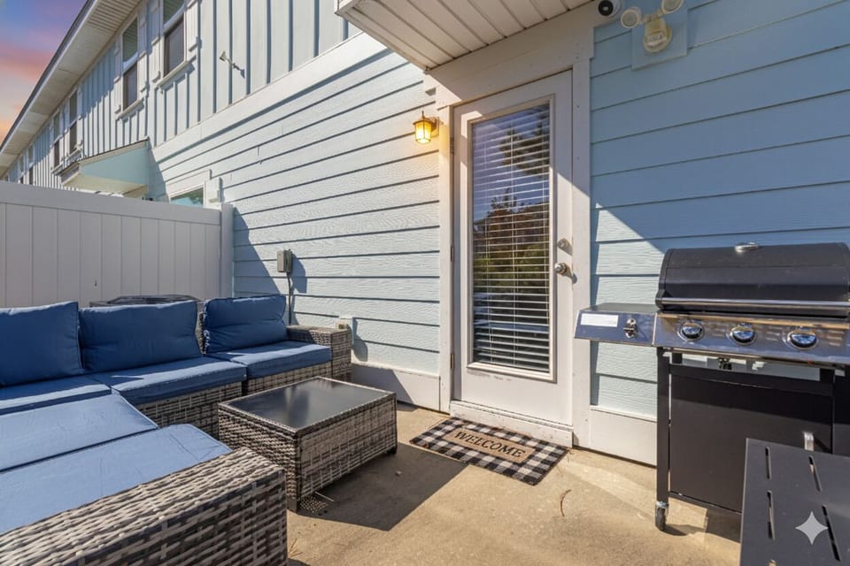 Private outdoor patio with comfortable lounge seating, fire pit table, and BBQ g