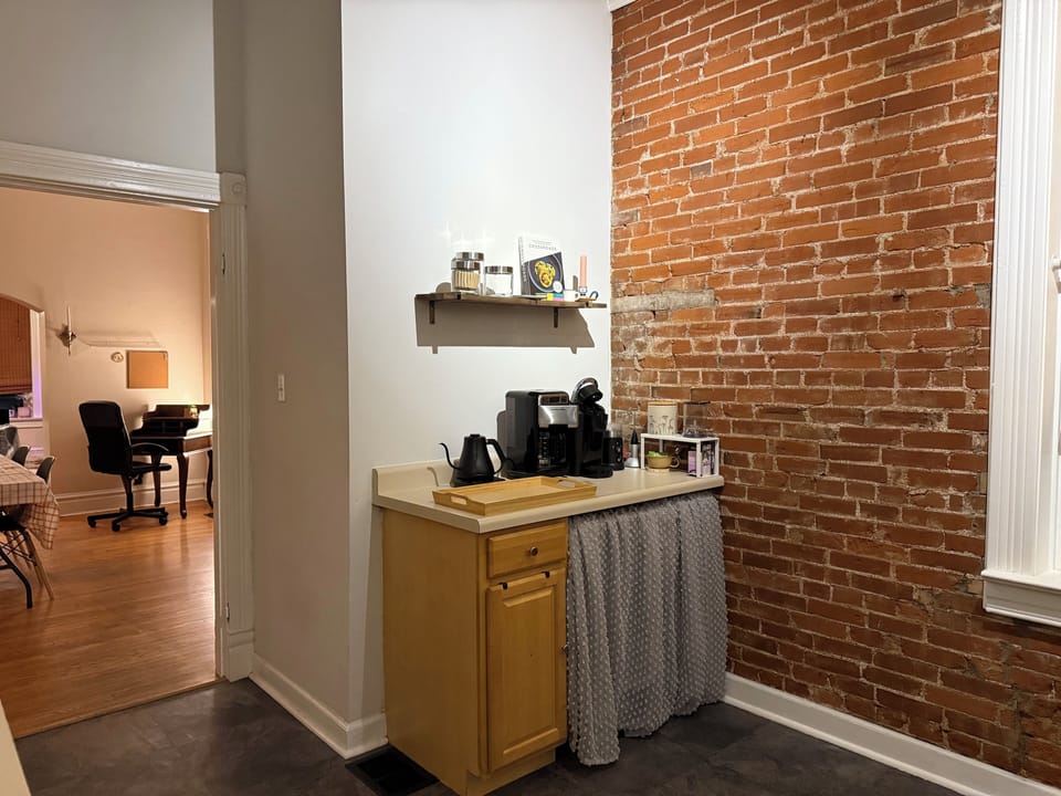 Coffee bar with keurig, coffee pot, coffee grinder, kettle, and scale.