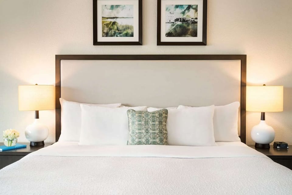 King bed with soft pillows, lamps, and framed wall art