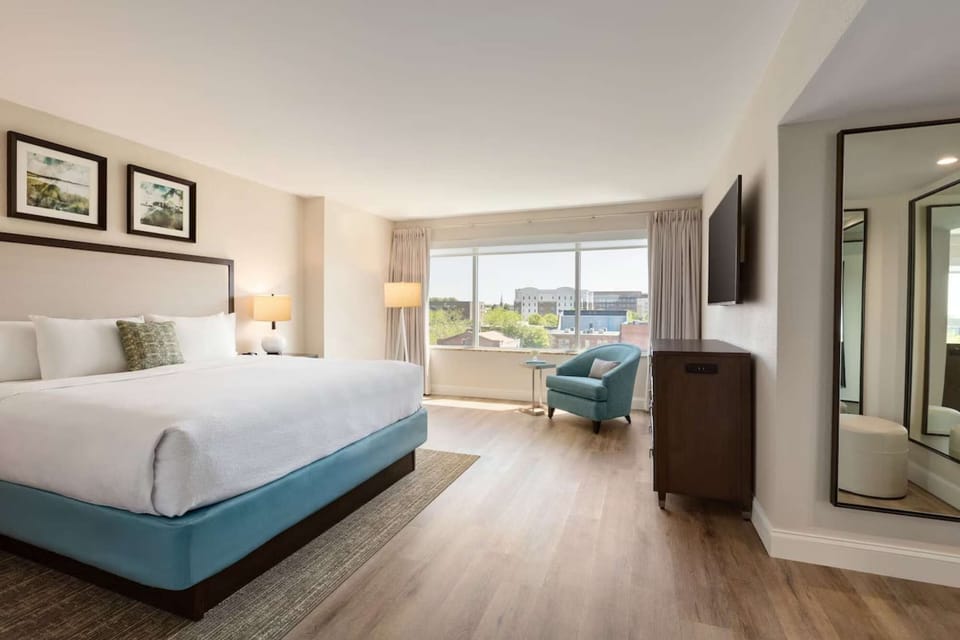 Spacious king room with armchair and city view through window