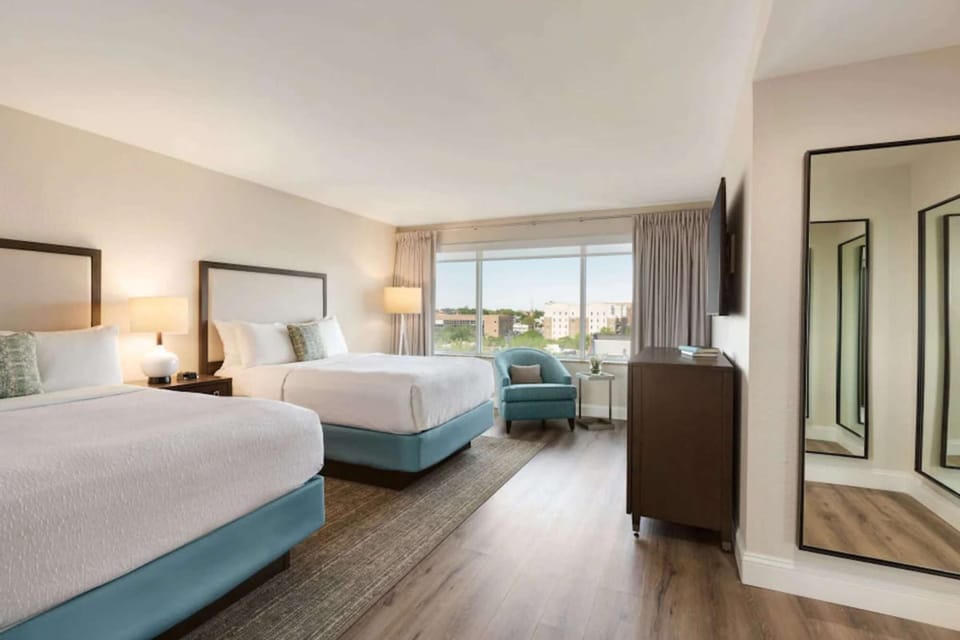 Spacious room with two beds, armchair, and large window view