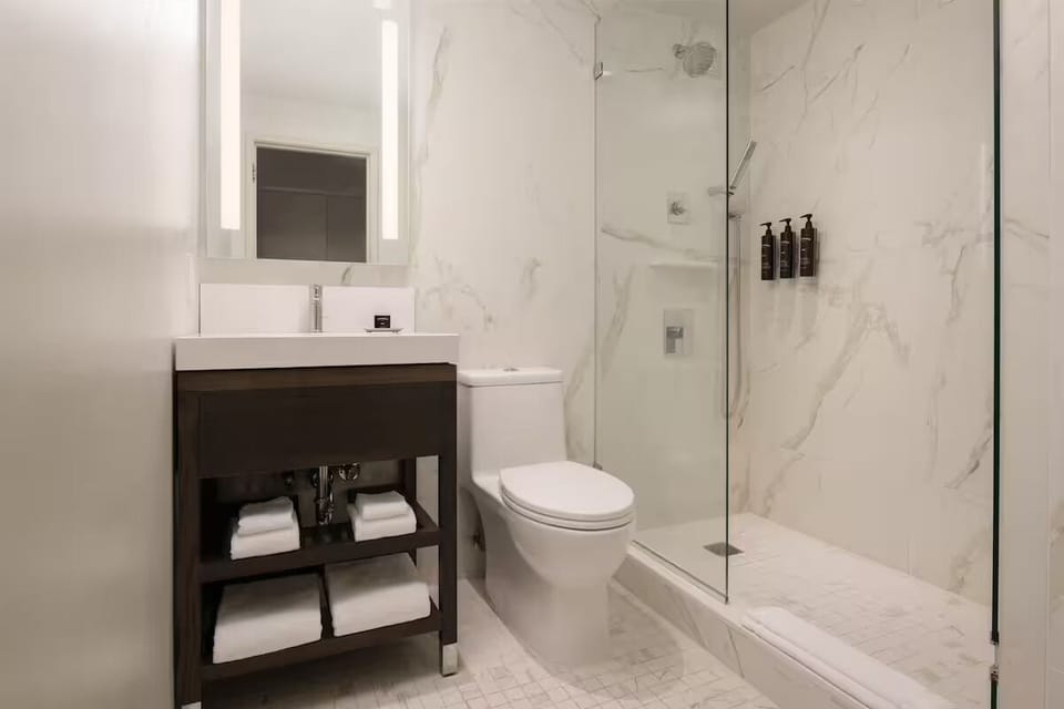 Refresh in a sleek marble shower with plush towels.