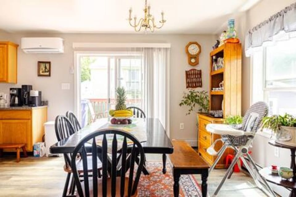 Bright family dining space with a large table, high chair, and sunny deck access — perfect for shared meals and morning coffee together.