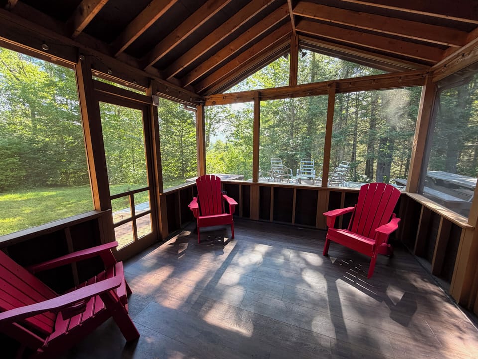Screened porch with Adirondack chairs and mountain views.