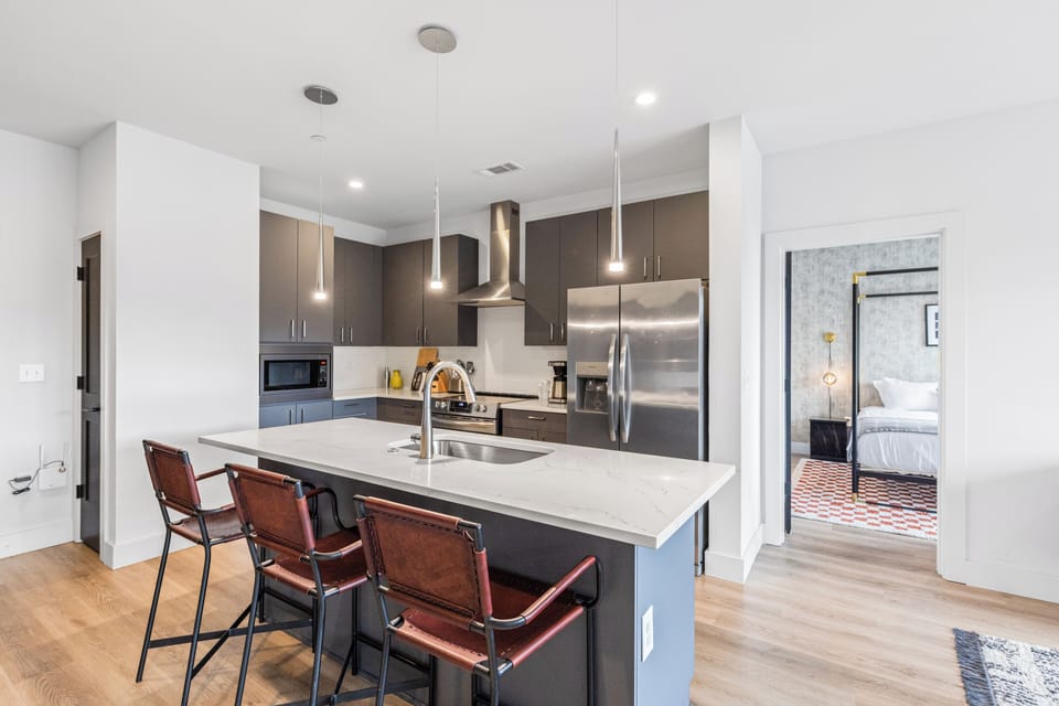 Modern kitchen with island seating and stainless steel appliances.