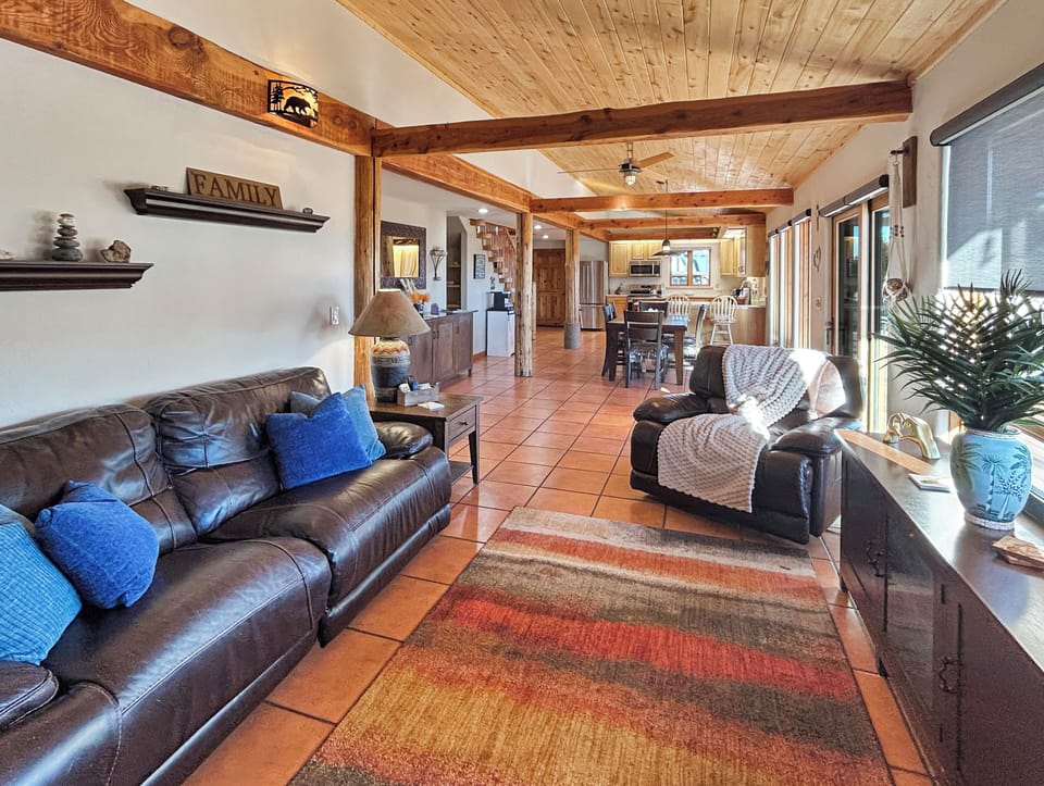 Step into your home away from home where rustic elegance meets modern comfort. Sink into plush leather seating beneath soaring wood-beam ceilings as natural light streams through expansive windows, creating the perfect space to unwind after your adventures