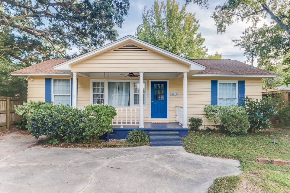 This charming beach home features a welcoming front porch surrounded by lush greenery, just two blocks from the pristine Gulf shoreline.