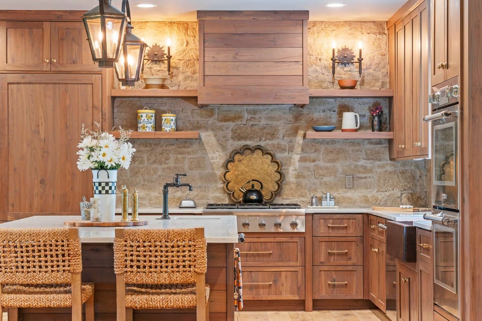 Elegant stone backsplash, open shelving, and brass details add mountain-modern character.